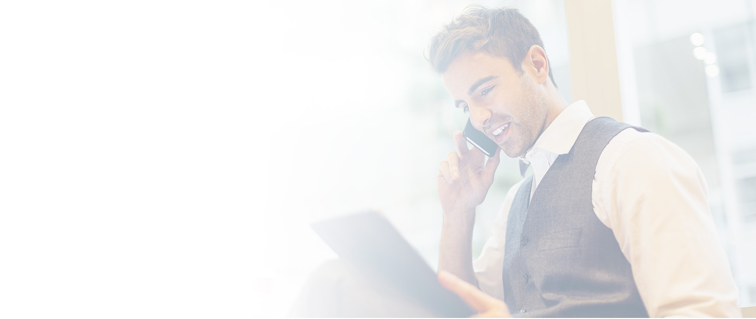 Giovane Private Banker commenta al telefono le informazioni che visualizza sul tablet.