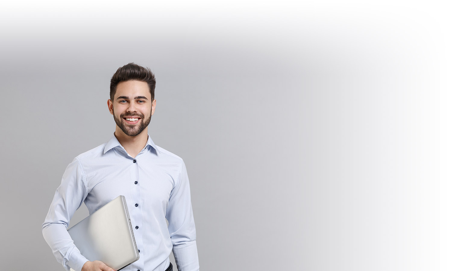 Giovane Private Banker sorride tenendo in mano un pc.