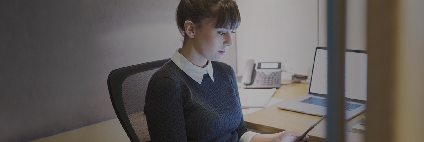 Giovane donna naviga con lo smartphone in ufficio.