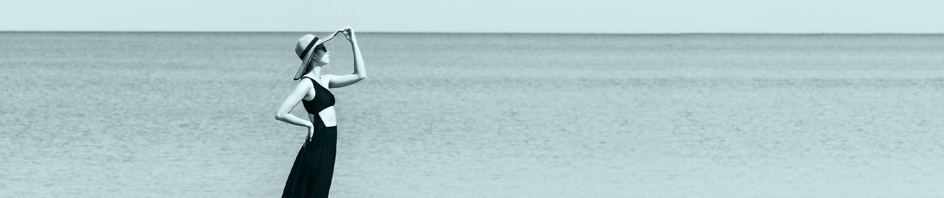 Ragazza con il cappello guarda il mare.